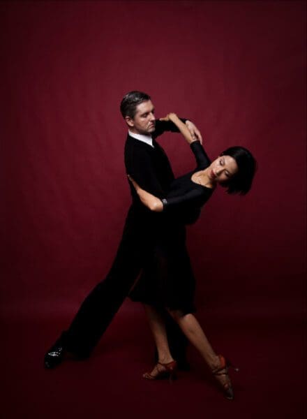 A man and woman dancing in black outfits.