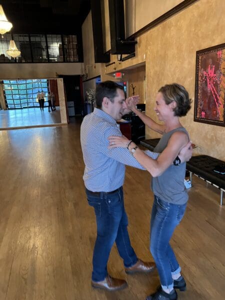 A man and woman dancing in the middle of an empty room.