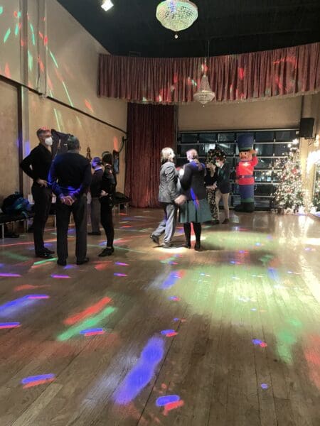 A group of people standing in the middle of an indoor dance floor.