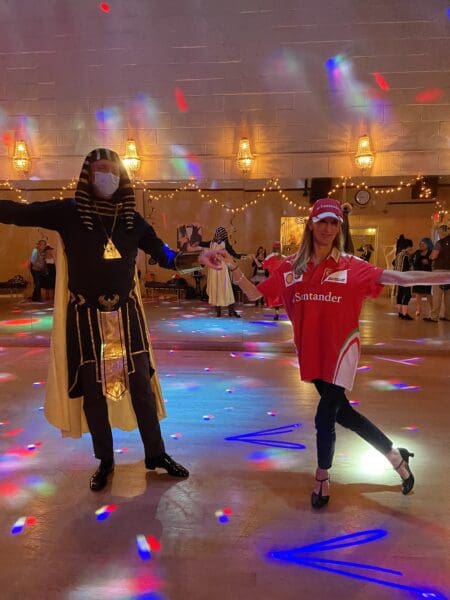 Two people in costumes dancing on a dance floor.