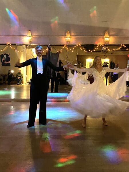 A man and woman in formal wear dancing on the dance floor.