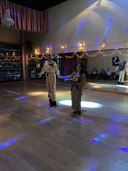 Two people are dancing in a room with lights.