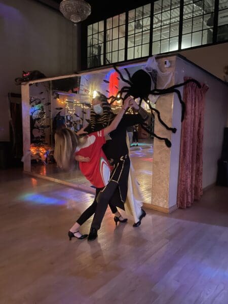 Two people dressed as spiders dance in a room.