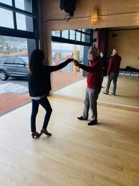 Two people are dancing in a room with mirrors.